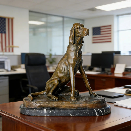 This stately bronze sculpture of a seated pointer dog is crafted using the traditional lost-wax casting method. The dog is portrayed in an alert upright pose, with its head slightly turned, expressing focus and refined poise characteristic of a hunting breed. The warm bronze patina highlights its lean musculature, smooth short coat, and detailed rope collar.