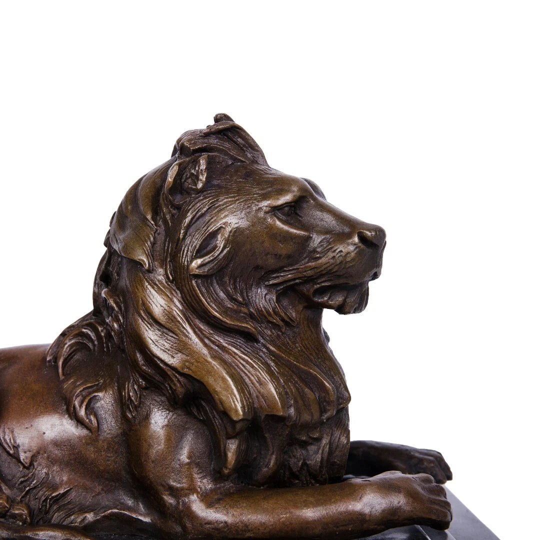 This is a majestic bronze lion sculpture, cast using the lost-wax method, depicting the animal in a poised, reclining stance. The sculpture features a rich, warm bronze patina with a smooth, polished finish that accentuates the lion’s powerful musculature and the intricate, flowing details of its mane. Its head is held high, conveying a sense of quiet authority and regal composure, while its body rests in a relaxed yet alert posture.