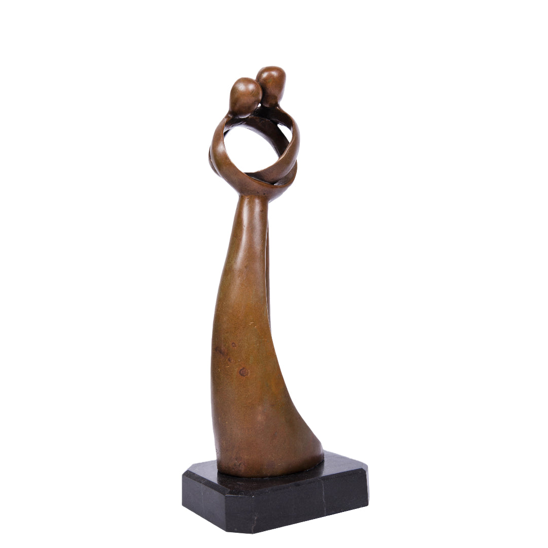 This abstract bronze sculpture captures an intimate moment between two figures in a minimalist and modern form. The elongated bodies rise gracefully from a solid stone base, while the upper structure forms a circular embrace, symbolizing unity and emotional connection.