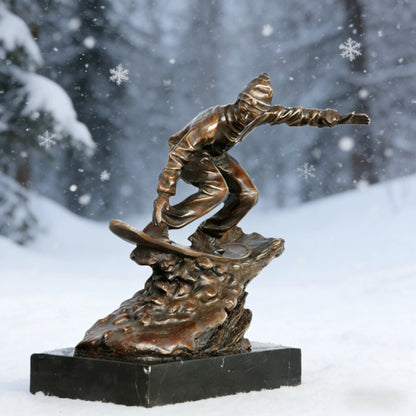 This is a dynamic bronze sculpture of a snowboarder, crafted using the lost-wax casting method. The piece captures the athlete mid-action, crouched low on their board while navigating a rugged, snow-like terrain, with one arm extended for balance. The rich, warm bronze patina accentuates the fluid folds of the snowboarder’s jacket and pants, as well as the textured, naturalistic base that simulates snowdrifts.
