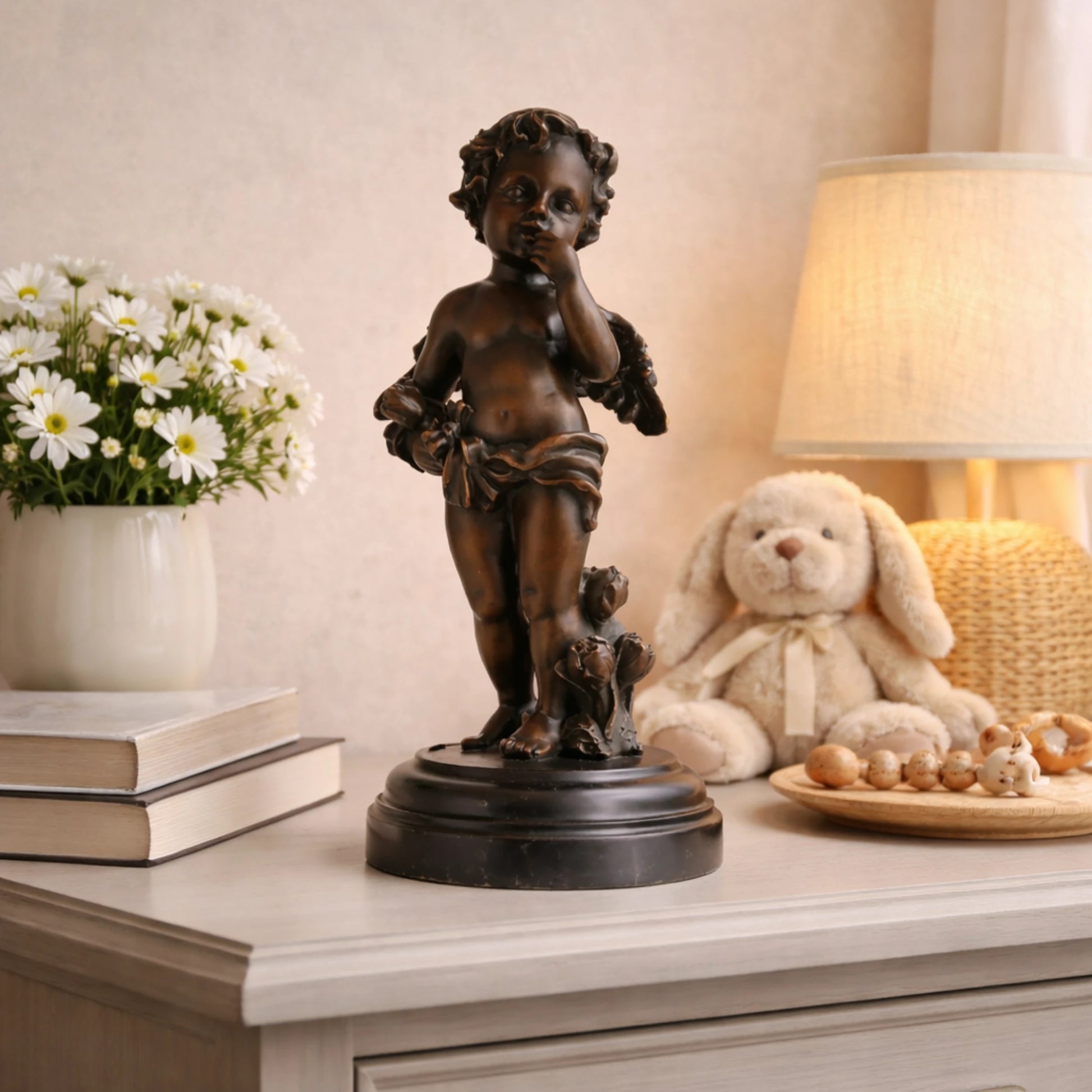 Classical bronze cherub statue standing on roses with finger to lips, winged cupid angel sculpture on circular black marble base, loss wax casting romantic art.