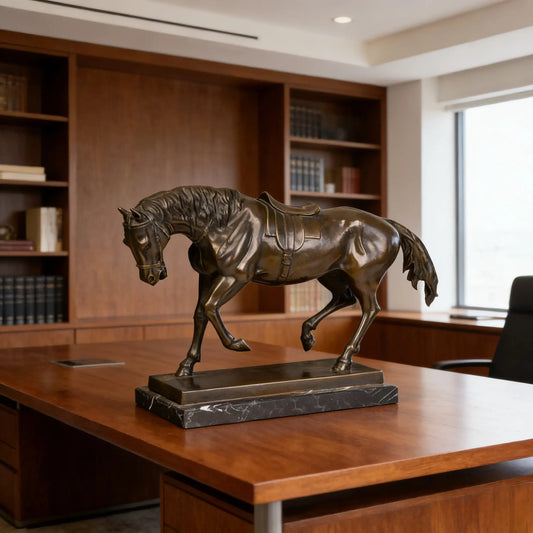 This is a refined bronze horse sculpture, cast using the lost-wax method, depicting the animal in a gentle, trotting stance with a Western-style saddle. The sculpture features a deep, rich bronze patina with a smooth, polished finish that accentuates the horse’s sleek musculature and fluid form. Its mane and tail are intricately detailed, flowing naturally, while the head is slightly bowed, conveying a sense of calm elegance and readiness. 
