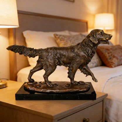 This is a dynamic bronze sculpture of a golden retriever, crafted using the lost-wax casting method. The piece captures the dog in mid-stride, moving forward with a purposeful gait, its head held high and tongue slightly lolling, conveying a sense of energy, alertness, and friendly enthusiasm. The rich, warm bronze patina accentuates the intricate, wavy texture of its long, flowing coat, the detailed musculature of its legs, and the naturalistic details of the pebbled ground beneath its paws.