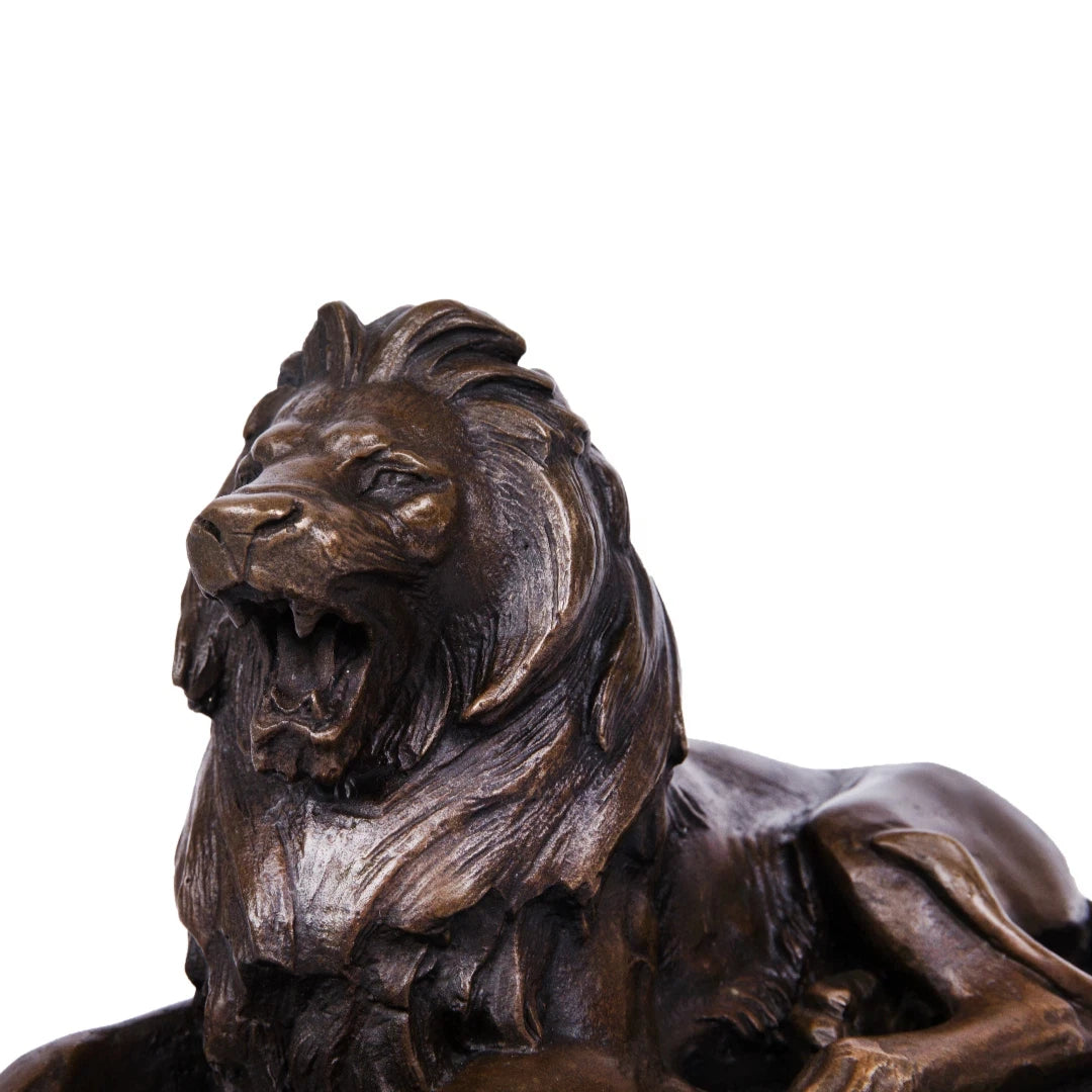 This is a powerful bronze lion sculpture, cast using the lost-wax method, depicting the animal in a reclining pose with its mouth open in a fierce roar. The sculpture features a rich, aged bronze patina that highlights the intricate, flowing details of its mane and the taut musculature of its body, conveying a sense of primal strength and authority. The lion’s head is raised, and its expression is intense, while its body rests in a relaxed yet alert posture, suggesting a moment of warning or dominance.