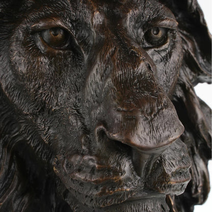 This is a powerful bronze bust of a lion, crafted using the lost-wax casting method. The sculpture focuses on the lion’s head and upper neck, capturing the animal in a moment of intense focus and regal authority. The deep, rich bronze patina accentuates the hyper-realistic details of the lion’s face—from the piercing gaze of its eyes and the rough texture of its whiskers to the intricate, flame-like folds of its mane, which appear to be caught in a powerful gust of wind.