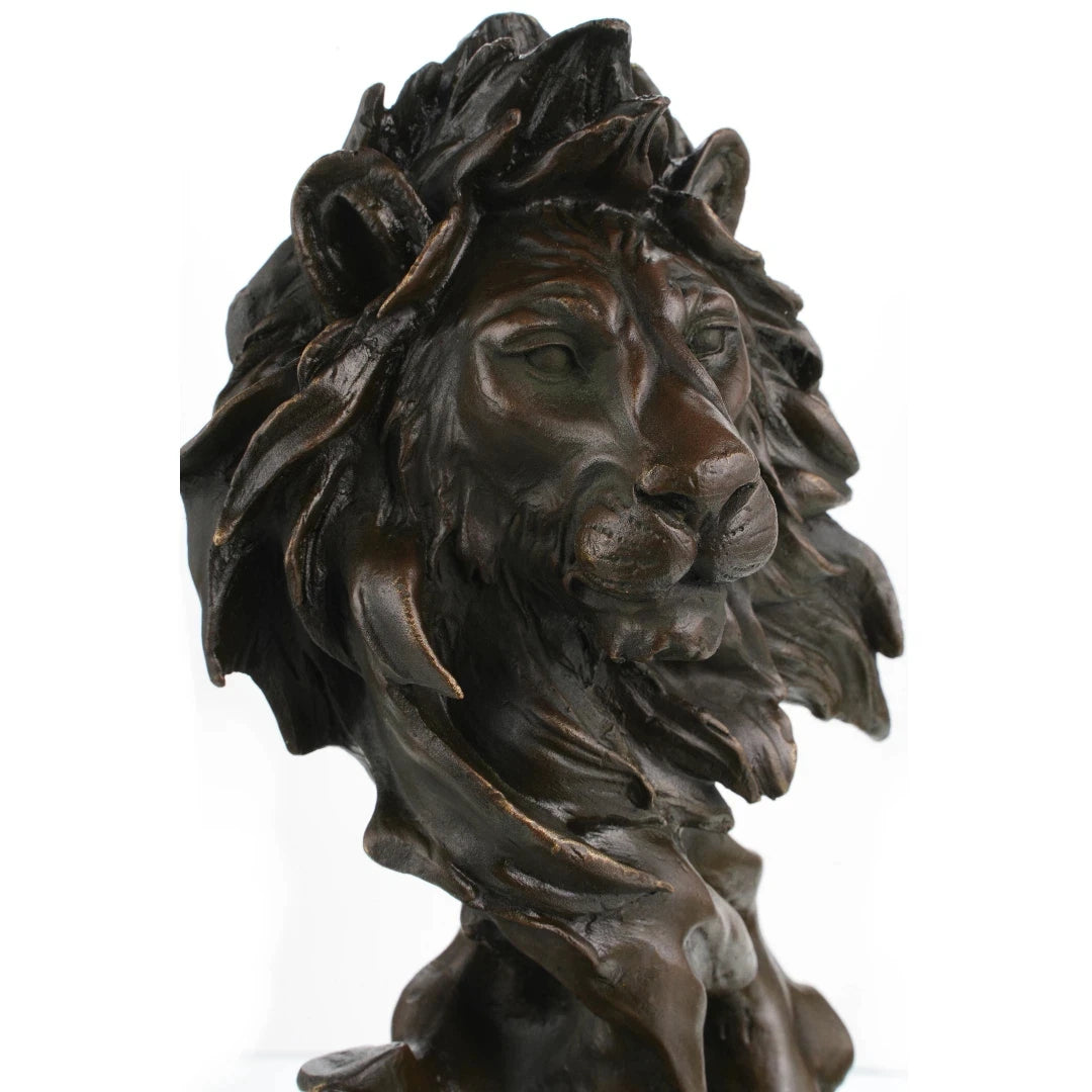 This is a striking bronze bust of a lion, crafted using the lost-wax casting method. The sculpture focuses on the lion’s head and upper neck, capturing the animal in a moment of quiet intensity, with its mane rendered in dynamic, flowing forms that suggest movement and raw power. The deep, rich bronze patina accentuates the intricate details of the lion’s facial features—from the intense gaze of its eyes to the texture of its whiskers—and the dramatic, almost wind-swept folds of its mane.